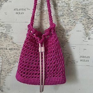 Embark on a global adventure with this charming pink crocheted bucket bag
